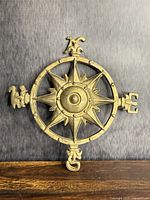 Front view of solid brass compass rose plaque placed on wooden surface and grey backdrop