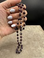 Photo showing the entire garnet beaded necklace held in hand to display bead size and color.