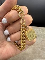 Curb link chain and locket attachment shown held against neutral background