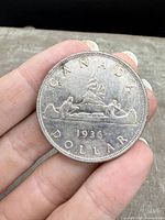 Reverse side showing canoe with voyageurs and year 1936.