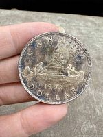 Front side of the 1953 Canadian Silver Dollar showing text "CANADA DOLLAR" and birch bark canoe design with rowers, dated 1953.