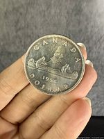 Front side of 1954 Canadian silver dollar showing canoe with two men and 'CANADA DOLLAR 1954' text