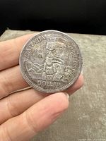 Front side of silver dollar showing Canadian Totem Pole and inscription indicating the 100th anniversary of British Columbia's confederation (1858-1958).
