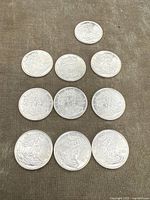 Top view of 10 American Silver Eagle coins arranged in pyramid shape on fabric surface.
