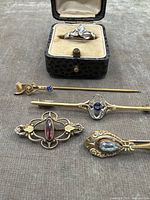 Five pieces including ring in box and four pins/brooches arranged on cloth