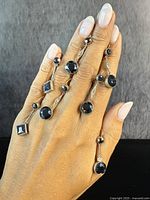 Close-up photo showing hand modeling multiple antique-style gold-tone hematite drop earrings with faceted black stones, showcasing different styles.