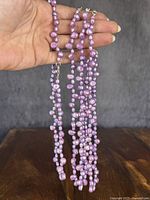 Four purple and pink freshwater pearl necklaces displayed together.