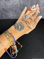 Photo showing multiple pieces of Indigenous American style sterling silver jewelry displayed on a hand including pendants, earrings, rings, and bracelets.