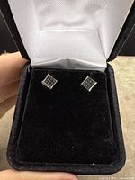 Pair of sterling silver stud earrings with blue diamonds in black velvet jewelry box.