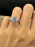 Ring on hand showing large clear round stone and split shank with small clear stones