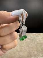 Front view showing the sparkling clear stones on the upper part and the vibrant green stones at the bottom of each earring.