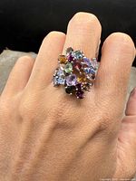 Front view of ring worn on finger showing clustered gemstones