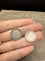 Obverse side showing King George V portraits on both silver 5 cent coins held in hand