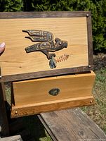 Wooden box with Raven carving on top lid, wood and natural finish, drawer opened, showing the box structure.