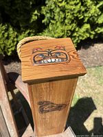 Top view showing carved and painted bear face on the lid with rope handle beside it.