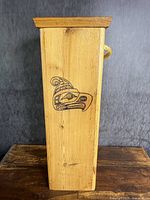 Side panel showing eagle or bird face painted in black line design on natural cedar wood