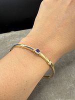 Bangle bracelet shown worn on wrist showing fit and design with visible amethyst stone.