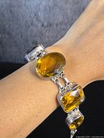 View of bracelet worn on wrist showing large faceted oval and rectangular amber gemstones.