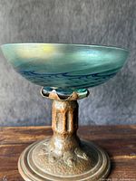 Front view of copper pedestal and glass bowl on wooden surface showing hammered texture and bowl finish
