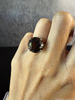 Front view of the large oval smokey quartz ring worn on finger showing the stone and silver band.