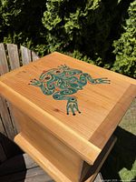 Top-down view of cedar box lid showing painted green and orange frog design.