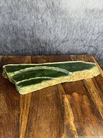 Horizontal top view of jade slab showing three carved grooves on a wooden surface