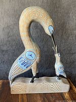 Full front view of sculpture showing large bird feeding chick