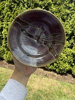 Top view of conical ceramic bowl showing dark glaze and abstract splash pattern inside.