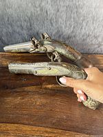 Pair of flintlock prop pistols side by side on wooden surface