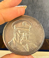 Close-up of one sterling silver medallion featuring Winston Churchill smoking a cigar and wearing a cap