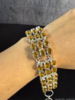 Bracelet worn on wrist showing multi-row design with numerous oval-shaped and round yellow citrine gemstones set in sterling silver.