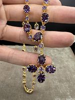 Front view of necklace chain and pendant held in hand against black background