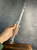 Photo of the full length of the flute/piccolo held in hand, showing the instrument from the mouthpiece to the foot joint.