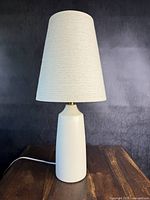 Full view of lamp showing off-white ceramic base and cream fabric shade