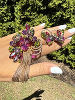 Brooch and earrings displayed on hand over greenery for scale and full set view