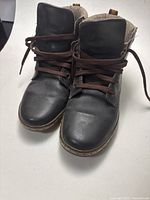 Front view of the pair of brown leather boots showing laces and toe area.