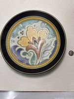 Top view of the decorative plate showing colorful floral design and dime for scale.