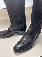 Front view showing black leather cowboy boots with detailed stitching and square toe design.