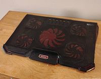 Full view of the black laptop cooling pad showing the mesh surface and five fans.