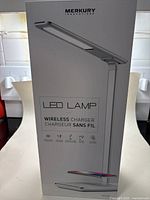 Front product box showing the LED lamp with wireless charger image and Merkury Innovations branding.