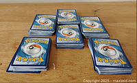 Stacks of Pokémon cards showing the blue Poké Ball back side, indicating the identity of the cards.