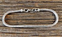 Men's foxtail chain bracelet lying flat on a wooden surface, showing the full length and the clasp.