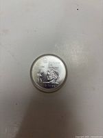 Front of silver coin showing Montreal 1976 Olympic design with torch and laurel-crowned figure