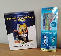 Photo showing the front of Gillette shaving kit box and Oral-B toothbrush pack with four toothbrushes in soft bristle variety.