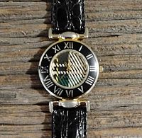 Front view of the round dial watch face showing Roman numerals and patterned inner dial, black faux-croc leather strap