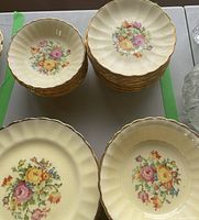 Photo showing stacked dinner and salad plates with floral design and gold rim.