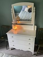 Frontal image showing white wooden dresser, mirror, and lamp on top with minor wear.