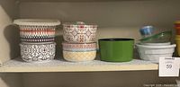 Shelf showing all storage containers and bowls arranged in two rows, showcasing variety of colorful ceramic and plastic items.