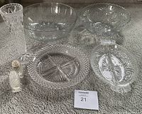 Image showing set of crystal and pressed glass pieces including tall vase, two bowls, divided dish, serving plate, and salt and pepper shakers on carpet