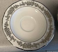 Close-up photo of a small plate with silver floral pattern and silver trimmed scalloped edge